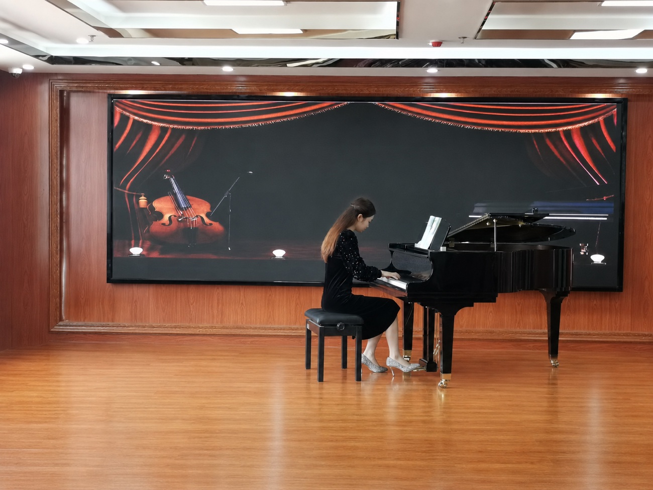 Mina at a grand piano on stage, part of her multidisciplinary musical training