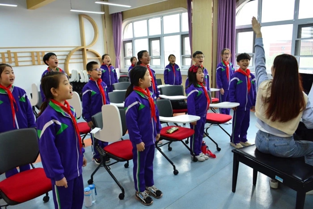 Mina leading a children's choir in a music classroom